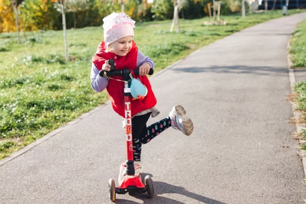 Egy kislány a parkban egy rollerrel